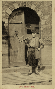 16202 Afbeelding van een klepperman in historische kleding voor de ingang van een nagemaakt gebouw op de historische ...